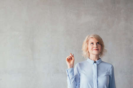 Successful business woman. Marketing design. Portrait of blonde mature lady over light wall, looking...