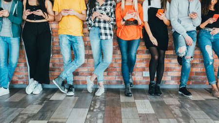 Digital age. Social media addiction. Row of friends colleagues with smartphones. Millennials lifestyle. Technology leisure.の写真素材