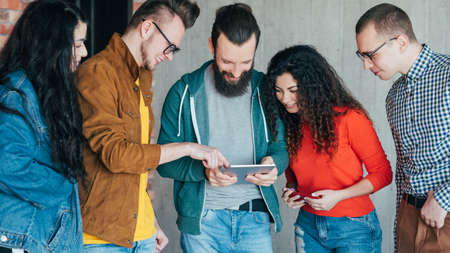 Millennials business meetup. IT workers discovering pacing technologies on tablet, discussing new...