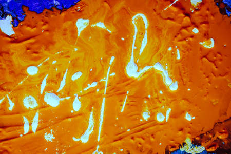 Abstract orange neon paint background. White stains spread chaotically over fluid liquid rough...