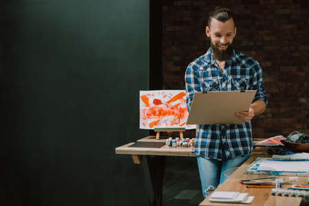 Artist delight. Smiling bearded guy with board panel. Painting gaining inspiration generating ideas mastering skills. Hobby.の写真素材