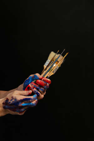 Man hands paint on holding bunch of paintbrushes. Hobby and professional occupation. Creativity...