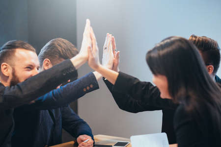 Successful teamwork and cooperation. Young professional team. Male and female business partners giving high five.の写真素材