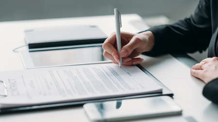 Modern business investment. Corporate relationship. Closeup of female hand signing contract.の写真素材