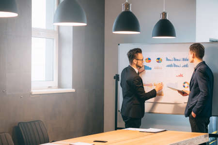 Business startup. Young male colleagues discussing project in modern loft conference room.の写真素材