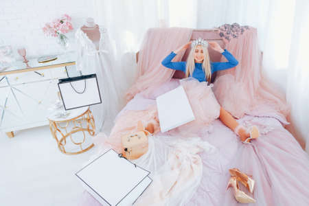 Rich girl leisure. Luxury lifestyle. Shopping addiction. Happy blonde lady wearing tiara, feeling like a princess with new gowns.の写真素材