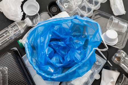 Waste management and disposal. Ecology problem. Empty plastic bag over flat lay of garbage.