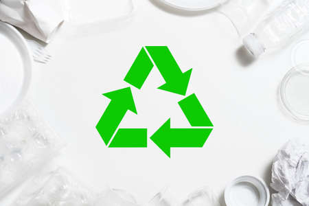 Garbage recycling. Environmental protection. Plastic tableware arranged around green symbol.