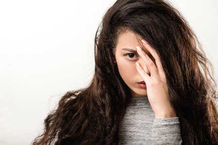 Depression trouble problem. Young woman looking camera. Hand hair covering eye. Intense look fixed...