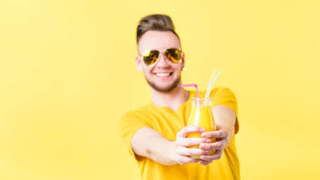 Excited young man offering bottle of fresh smoothie. Healthy nutrition weight loss dieting. Cold pressed vegan refreshmentの写真素材