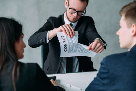 Renege on the agreement. Failed partnership. Young business man breaking deal, tearing up contract...