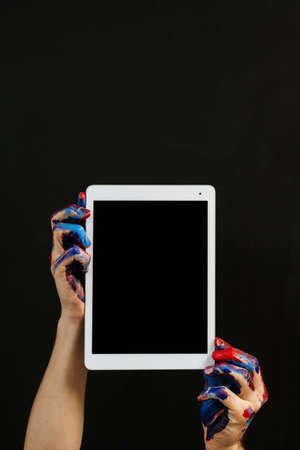 Online art school. E-learning. Painting classes. Tablet mockup in man hands smeared with paint. Graphic design courses.の写真素材
