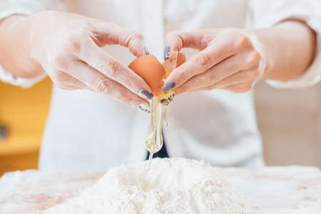 Bakery food and pastry cooking. Culinary master class. Closeup of female hands cracking egg straight...