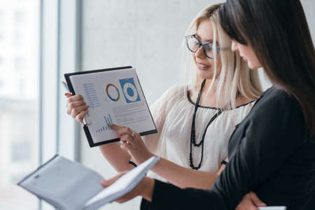 Successful business women. Young lady performing analytics report to her female boss.の写真素材