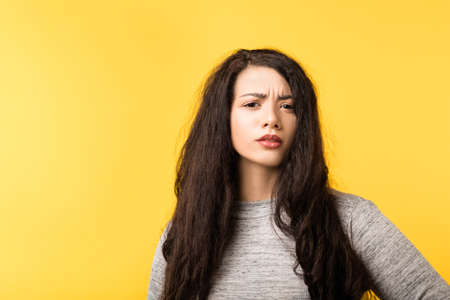 Pretty young woman looking at camera frowning. Skepticism doubt facial expression. Suspicious wary incredulous emotion.の写真素材