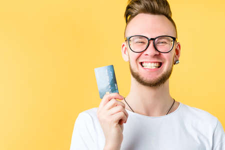 Banking service. Business loan. Startup financing. Portrait of young ambitious guy holding credit card, smiling.の写真素材