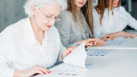 Board of directors. Business women sitting in row examining infographics documents. Getting ready...