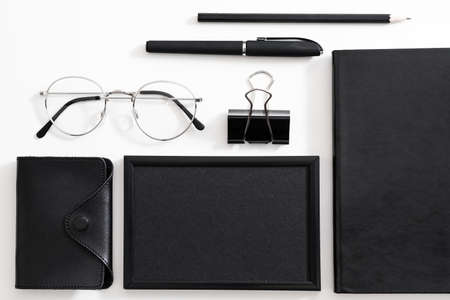 Business man workplace. Eyeglasses, black stationery and office supplies arranged over white...