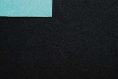 Sky blue felt texture patch at left top corner over dark fibers surface. Abstract art background. Empty space.の写真素材