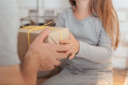 Happy family. Father and daughter relationship. Cropped shot of little girl receiving wrapped gift from loving dad.の写真素材