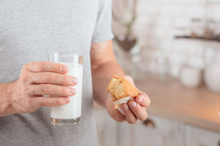 Healthy lunch. Cropped shot of man eating muffin with soy milk for breakfast. Blur kitchen...
