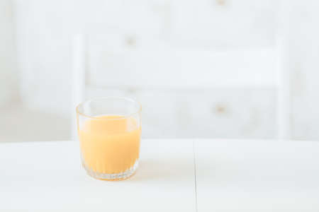Healthy diet. Balanced nutrition breakfast. Glass of orange juice on white table in kitchen. Blur background. Copy space.の写真素材