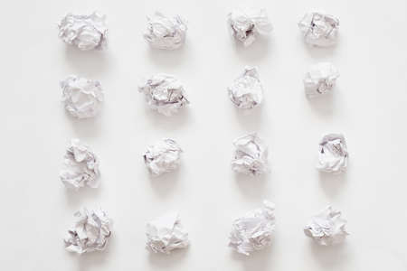 Waste recycling. Flat lay of crumpled paper ball rows on white surface. Abstract background.の写真素材