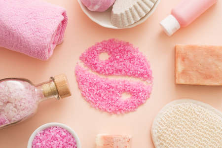 Oriental spa therapy. Flat lay of natural cosmetic products arranged around pink bath salt yin yang...