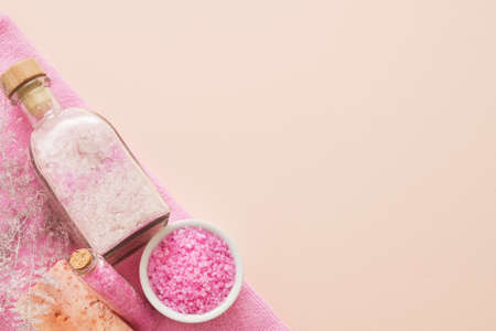 Home spa therapy. Top view of organic pink bath salt and handmade soap bar on peach background. Copy...