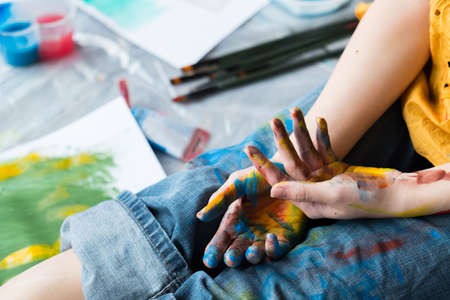 Creativity crisis. Cropped shot of artist sitting with hands and jeans dirty with colorful paint.の写真素材