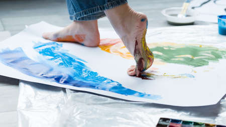 Painting art school. Closeup of artist feet walking on paper, creating colorful abstract artwork.の写真素材