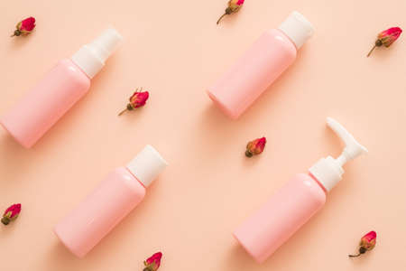 Rose essential oil natural cosmetic products. Travel kit mockup plastic bottles. Floral pattern peach background.の写真素材