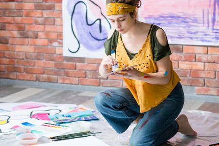 Hobby and recreation. Side view of lady sitting on floor, painting abstract artworks. Copy space.の写真素材