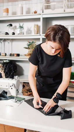 Tailor workshop. Seamstress drafting fabric pattern in modern studio. Jeans manufacturing.