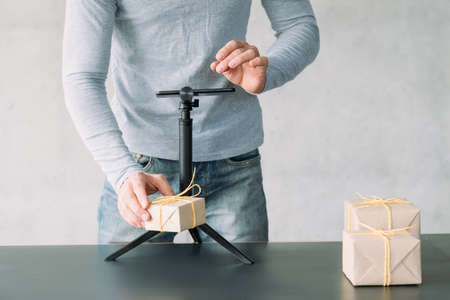 Online advertising. Cropped shot of man using smartphone on tripod to take picture of goods in gift boxes. Copy space.の写真素材