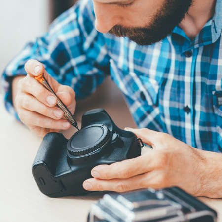 Photographing equipment maintenance and repair. Male engineer working on disassembled photo camera.の写真素材