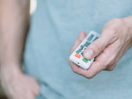 Wireless electronic devices. Closeup of remote control in male hand. Man switching program.の写真素材