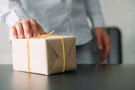 Goods delivery service. Closeup of paper wrapped box on office desk. Business man received package. Copy space.の写真素材