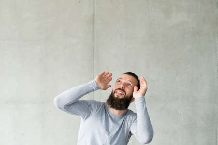 Portrait of scared bearded hipster guy with disturbed facial expression. Gray wall background. Copy space.の写真素材