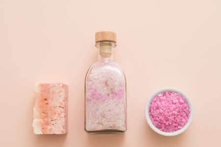 Home spa therapy. Flat lay of organic pink bath salt and handmade soap bar on peach background. Copy space.の写真素材