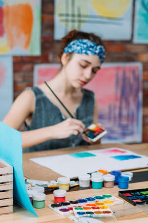 Artist workplace. Young female painter creating abstract artworks in studio. Blur background.の写真素材