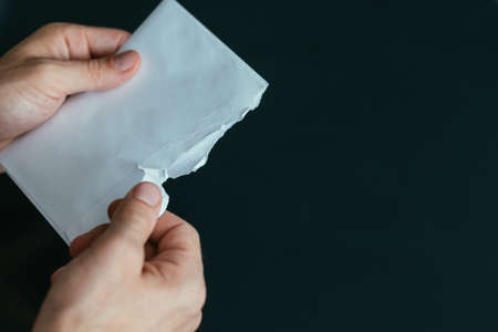 Business correspondence. Closeup of man hands holding envelope with written notice over dark background. Copy space.の写真素材