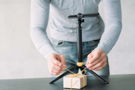 Online marketing. Cropped shot of man using smartphone on tripod to take picture of gift box. Copy...
