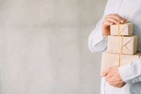 Online gift shop. Delivery service. Cropped shot of business man holding paper wrapped boxes. Gray...