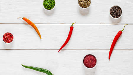 Flat lay of colorful chili, spices and flavoring on white wooden background. Copy space.の写真素材