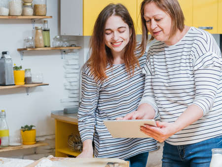 Bakery food and pastry cooking. Mother and daughter using tablet to search recipe.
