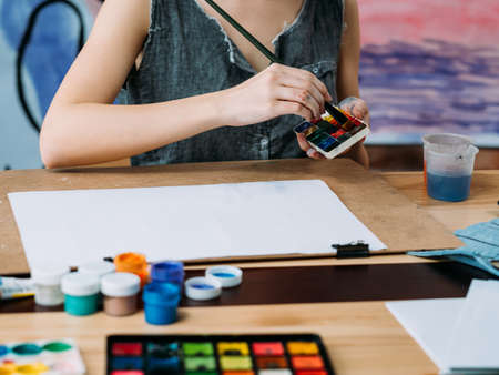 Hobby and leisure. Cropped shot of female artist painting with watercolor in modern workshop.の写真素材