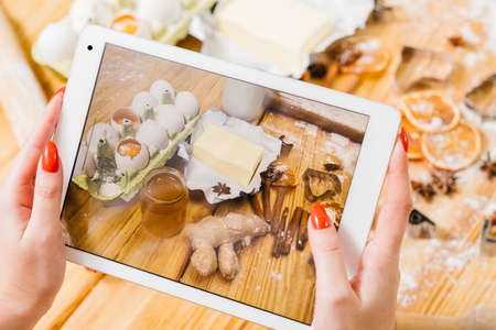 Gingerbread biscuit recipe. Lady using tablet to take picture of pastry ingredients.の写真素材
