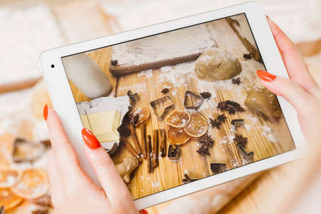 Online culinary recipe. Top view of tablet screen with pastry ingredients. Lady recording steps of making biscuits.の写真素材