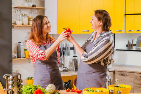 Home fun culinary course. Mother teaching her adult daughter to choose organic vegetables for eating.の写真素材